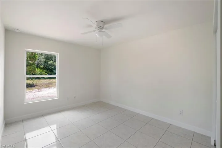 Tiled empty room with a healthy amount of sunlight and ceiling fan