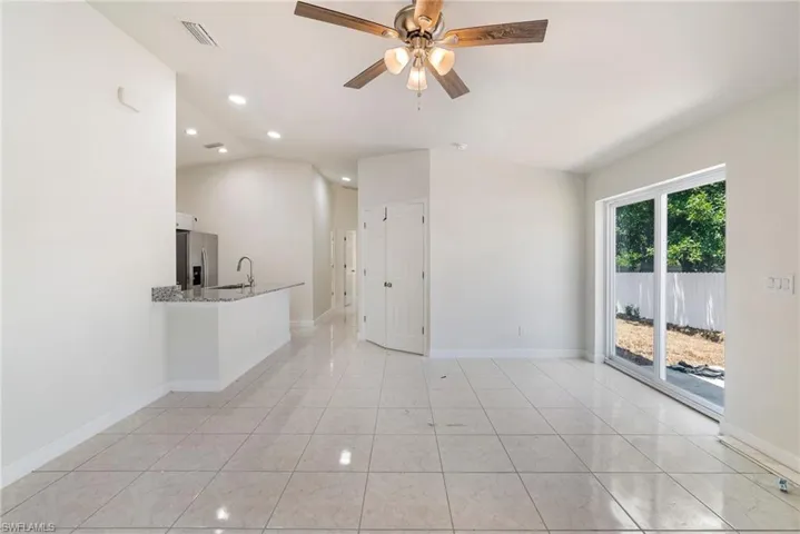 Unfurnished living room featuring sink, lofted ceiling, light tile flooring, and ceiling fan