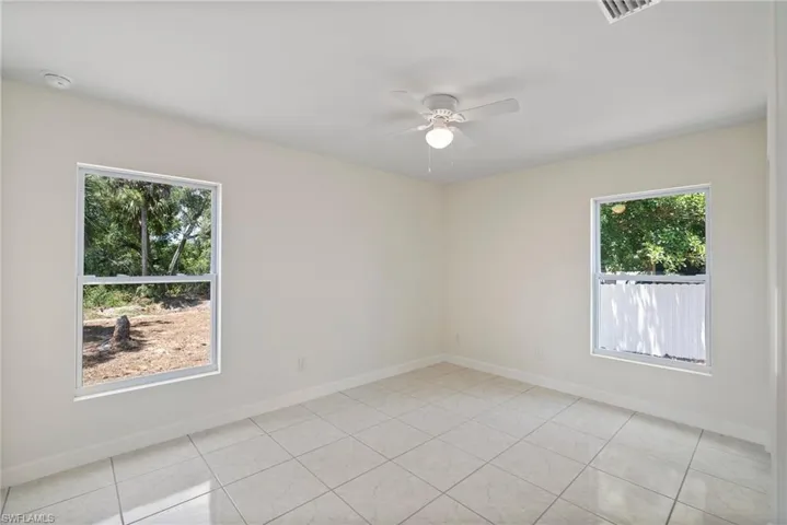 Empty room featuring a healthy amount of sunlight, ceiling fan, and light tile flooring