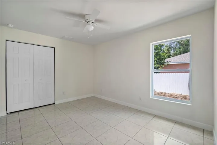 Unfurnished bedroom with ceiling fan, a closet, and light tile floors
