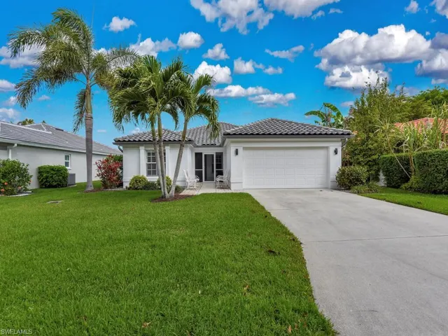 Front of home featuring landscaping, walkway and palm trees