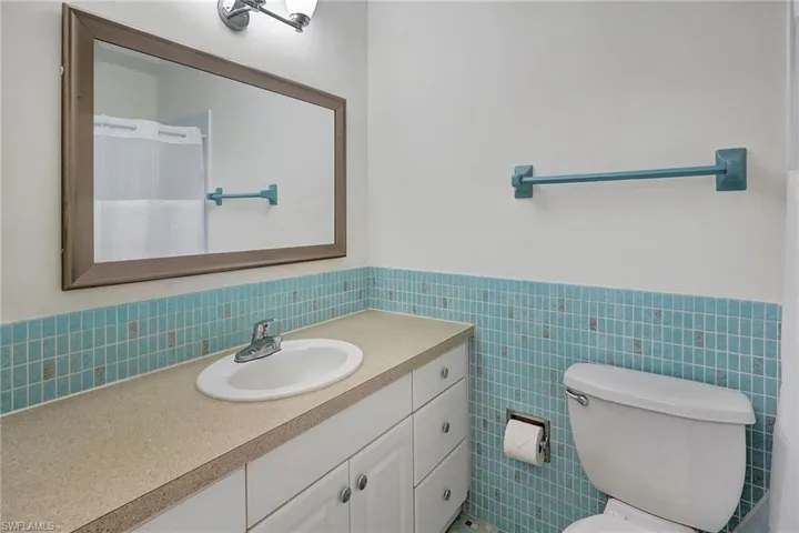 Master bathroom has fabulous retro blue tile and a bathfitter shower enclosure can be seen in the mirror reflection.