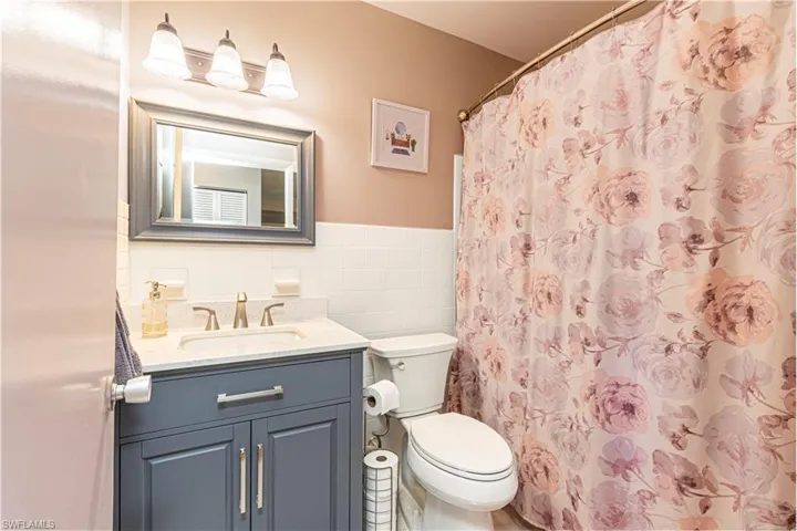 Bathroom with tile walls, tasteful backsplash, walk in shower, vanity, and toilet