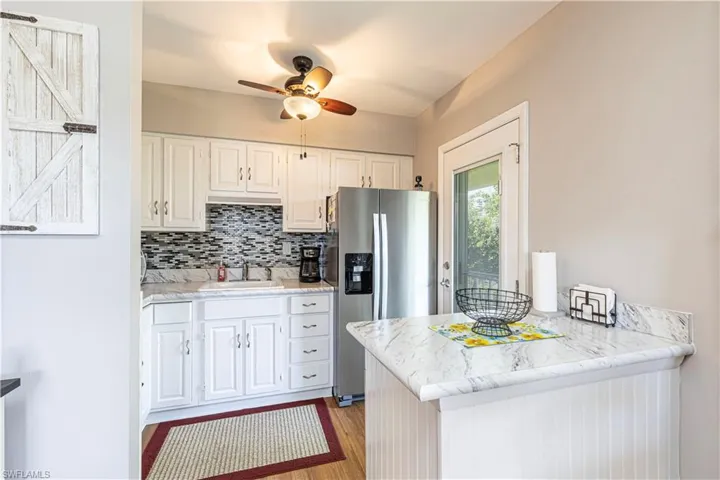 Kitchen featuring sink, white cabinets, stainless steel refrigerator with ice dispenser, kitchen peninsula, and ceiling fan