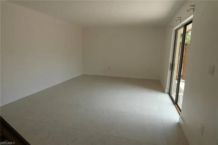 Spacious room featuring tile flooring, white baseboards, and a sliding glass door with black framing and hardware