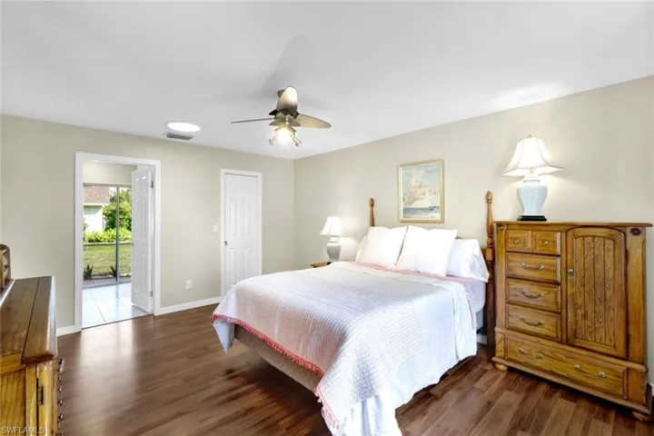 Bedroom with ceiling fan, dark hardwood / wood-style floors, and access to exterior
