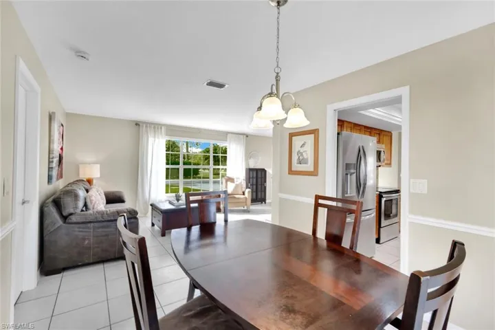 Dining area with light tile patterned flooring and a notable chandelier