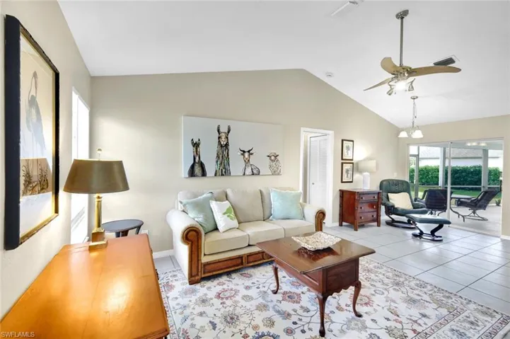 Living room with light tile patterned floors, vaulted ceiling, and ceiling fan