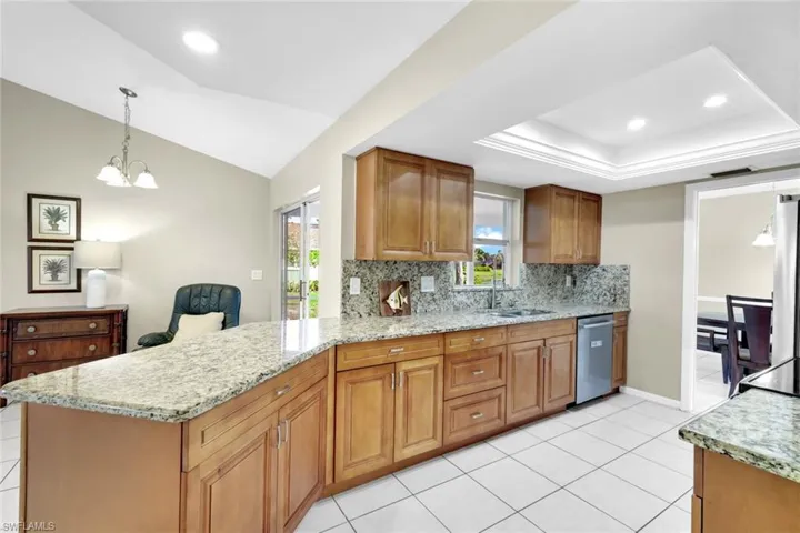 Kitchen with decorative light fixtures, sink, decorative backsplash, stainless steel dishwasher, and kitchen peninsula