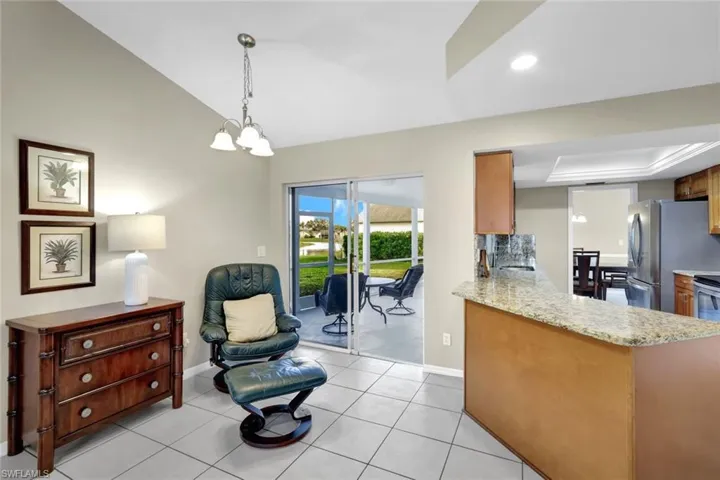 Kitchen with stainless steel refrigerator, decorative light fixtures, vaulted ceiling, kitchen peninsula, and a chandelier