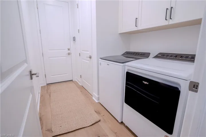 Laundry area with cabinets, light hardwood / wood-style floors, and independent washer and dryer