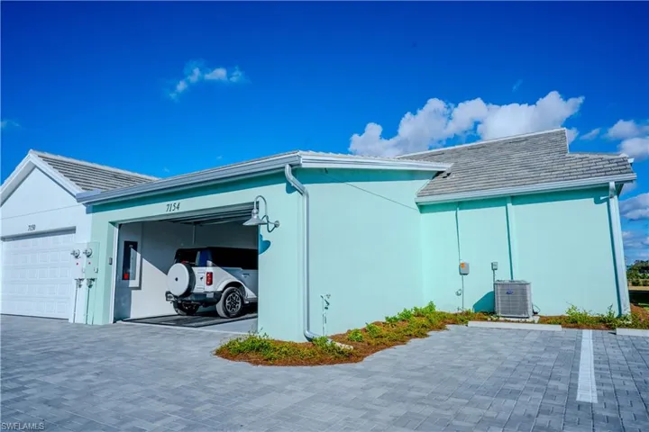 View of side of property with cooling unit and a garage