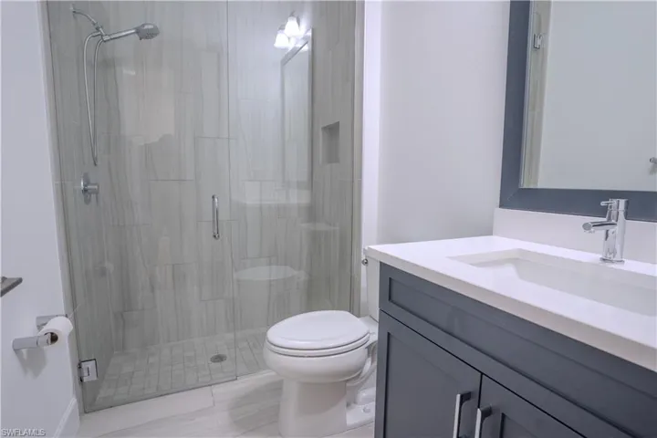 Bathroom featuring a shower with shower door, vanity, and toilet
