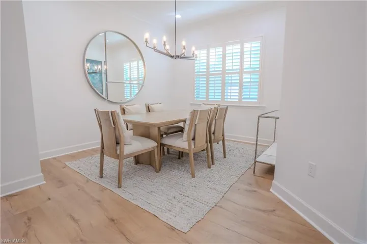 Dining space featuring light hardwood / wood-style flooring, a notable chandelier, and crown molding
