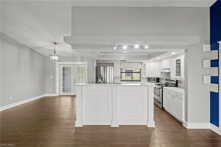 Kitchen featuring stainless steel appliances, a sink, wood tiled floors, and baseboards