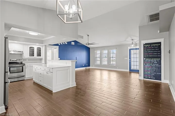 Kitchen featuring appliances with stainless steel finishes, white cabinetry, baseboards, and light countertops