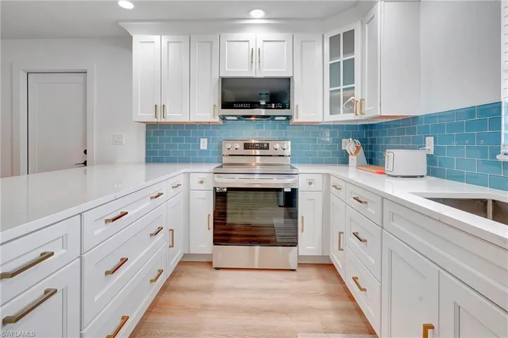 Kitchen featuring light wood-type flooring, white cabinetry, tasteful backsplash, and appliances with stainless steel finishes
