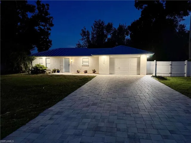 Single story home featuring a garage, decorative driveway, a gate, and a metal roof