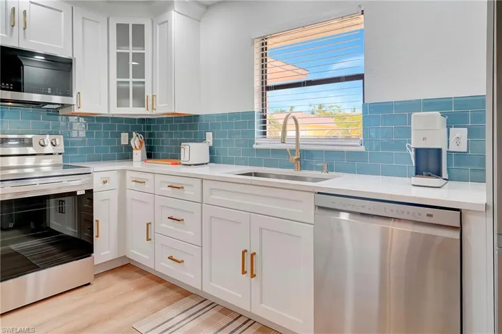 Kitchen featuring sink, white cabinets, light wood-type flooring, and appliances with stainless steel finishes