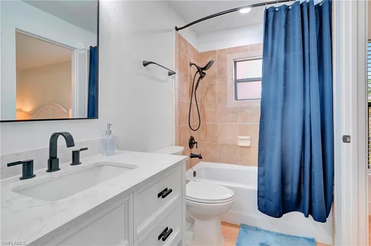 Full bathroom with toilet, vanity, and shower / bath combo