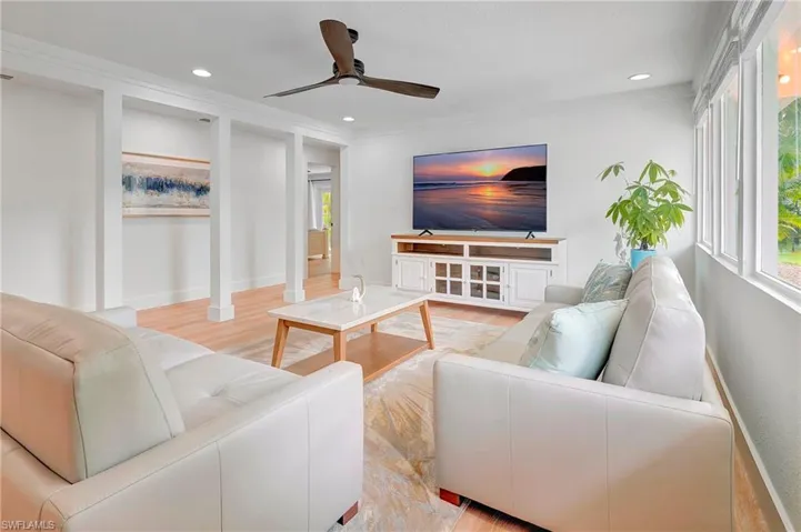 Living room featuring light hardwood / wood-style floors, ornate columns, ceiling fan, and ornamental molding