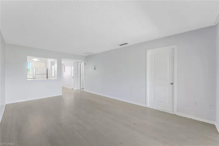 Empty room with a textured ceiling and light hardwood / wood-style floors