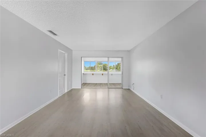 Empty room with hardwood / wood-style floors and a textured ceiling