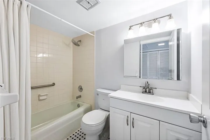 Full bathroom featuring tile patterned floors, toilet, shower / bath combination with curtain, and vanity