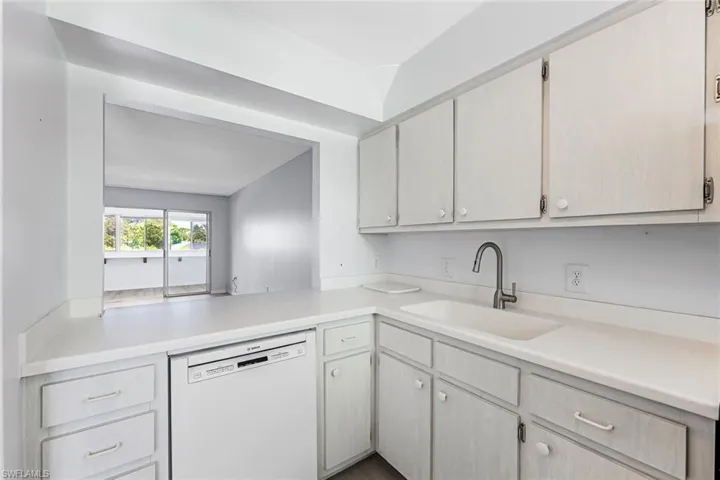 Kitchen with dishwasher, vaulted ceiling, light brown cabinets, and sink