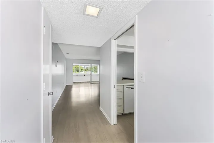 Corridor with light hardwood / wood-style floors and a textured ceiling