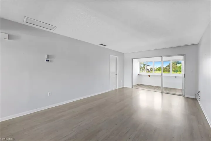 Empty room with a textured ceiling and hardwood / wood-style flooring