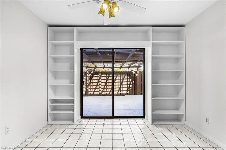 Built in shelving for books, artwork, decorative items flank the sliding doors the enter the private pergola covered patio.