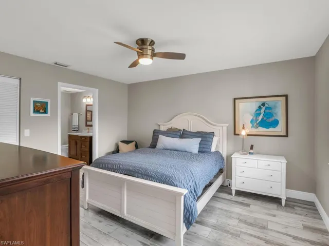 Bedroom featuring light hardwood / wood-style flooring, ceiling fan, and ensuite bath