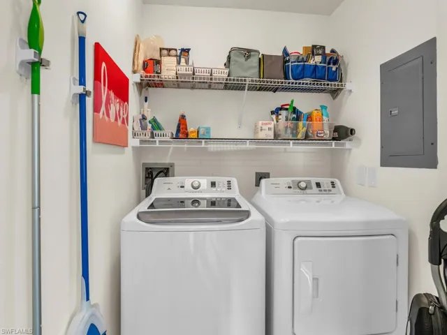 Laundry room with electric panel and washer and clothes dryer