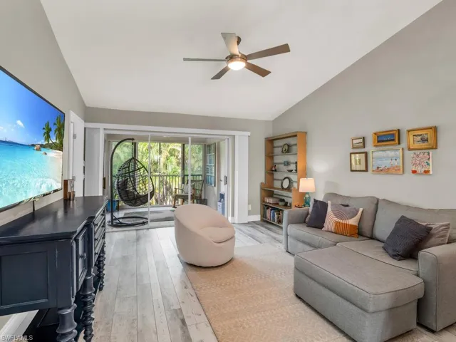 Living room featuring lofted ceiling, ceiling fan, and light hardwood / wood-style flooring