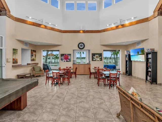 Tiled dining area with rail lighting, plenty of natural light, and a towering ceiling