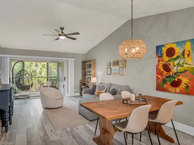 Dining area with ceiling fan with notable chandelier, light wood-type flooring, and high vaulted ceiling