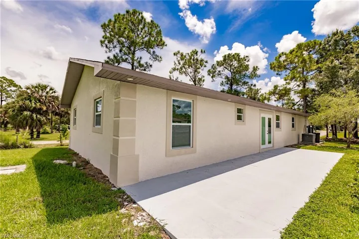 View of side of home featuring french doors, central AC unit, and a yard