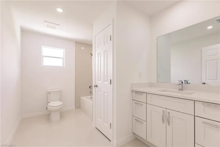 Full bathroom with washtub / shower combination, tile patterned flooring, toilet, and vanity