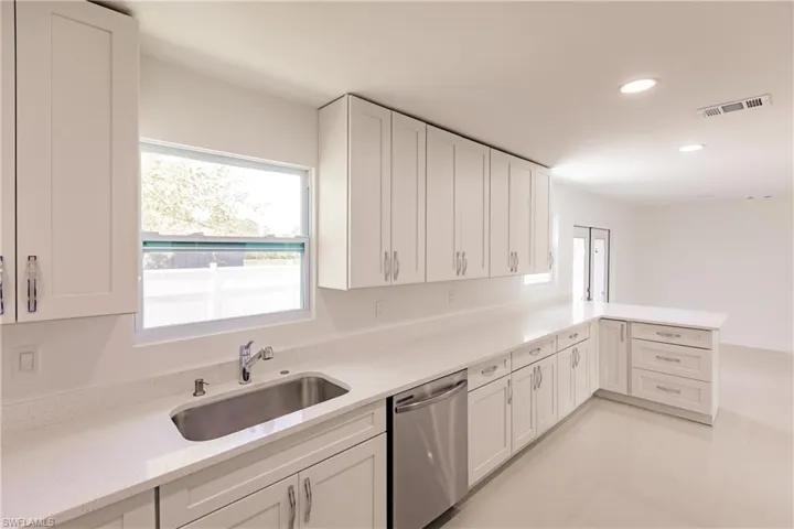 Kitchen with white cabinets, light tile patterned floors, sink, and stainless steel dishwasher