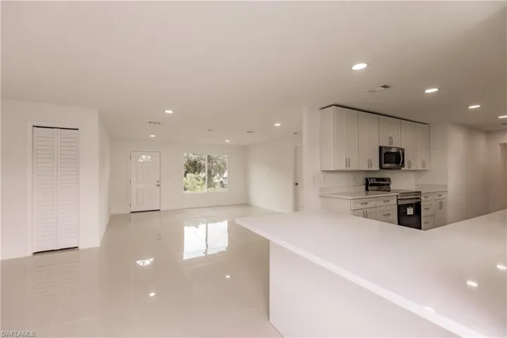 Kitchen featuring white cabinets, stainless steel appliances, and light tile patterned flooring