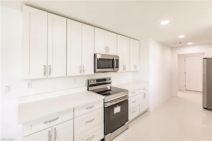 Kitchen with appliances with stainless steel finishes, light tile patterned floors, and white cabinets