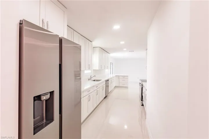 Kitchen with appliances with stainless steel finishes, white cabinetry, light tile patterned floors, and sink