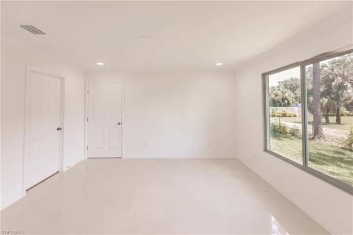 Empty room with light tile patterned floors, crown molding, and a healthy amount of sunlight