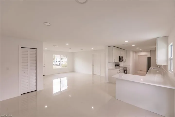 Kitchen featuring appliances with stainless steel finishes, white cabinetry, sink, kitchen peninsula, and light tile patterned flooring