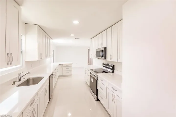 Kitchen featuring white cabinets, appliances with stainless steel finishes, light tile patterned floors, and sink