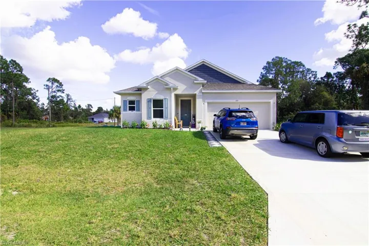 View of front facade featuring concrete driveway, a front yard, and a garage