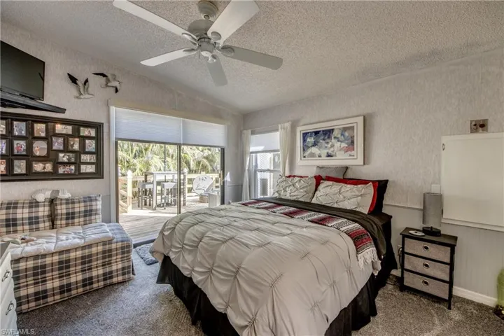 Bedroom featuring vaulted ceiling, access to exterior, a textured ceiling, light carpet, and ceiling fan
