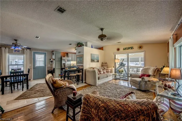 Living room featuring a textured ceiling, vaulted ceiling, ceiling fan, and light hardwood / wood-style flooring