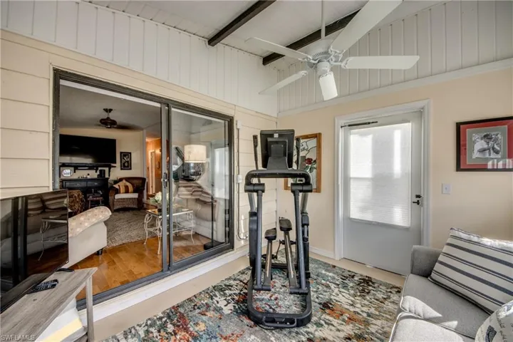 Workout room featuring wooden walls, ceiling fan, and vaulted ceiling